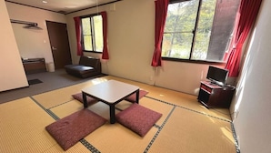 A room with tatami mats, a sofa, a table, and a TV stand. - Tairappyouchaya (Yuzawa)