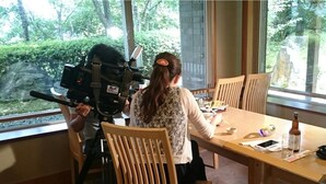 Une pièce avec une grande fenêtre, une table en bois et un appareil photo posé sur un trépied.