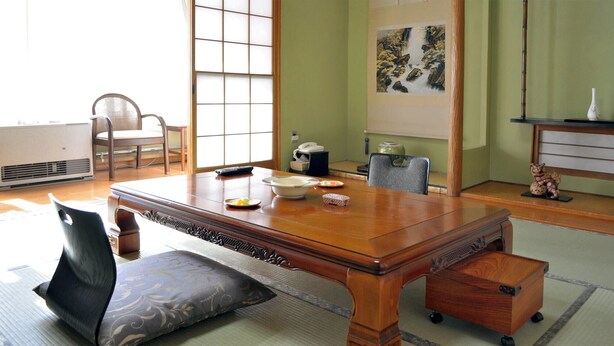 Una habitación tradicional japonesa con suelo de tatami, una mesa de madera baja y una puerta corredera tipo shoji.