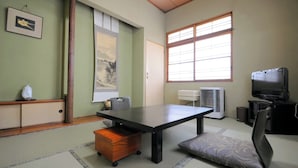 Una habitación con una mesa, una silla, un televisor y una ventana.