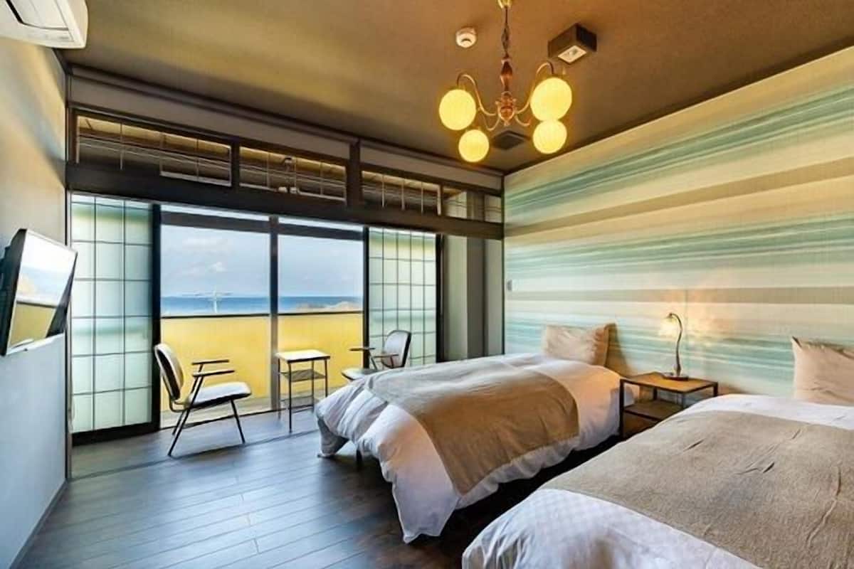 Ein Hotelzimmer mit einer großen Schiebetür, einem Bett, einem Nachttisch und einem Sessel.