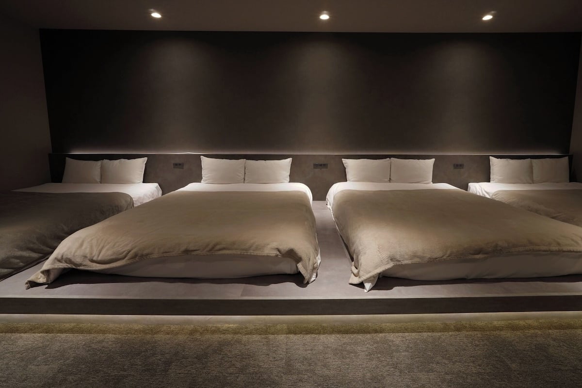 A modern hotel room with a large bed, two bedside tables, and a headboard with built-in lighting.