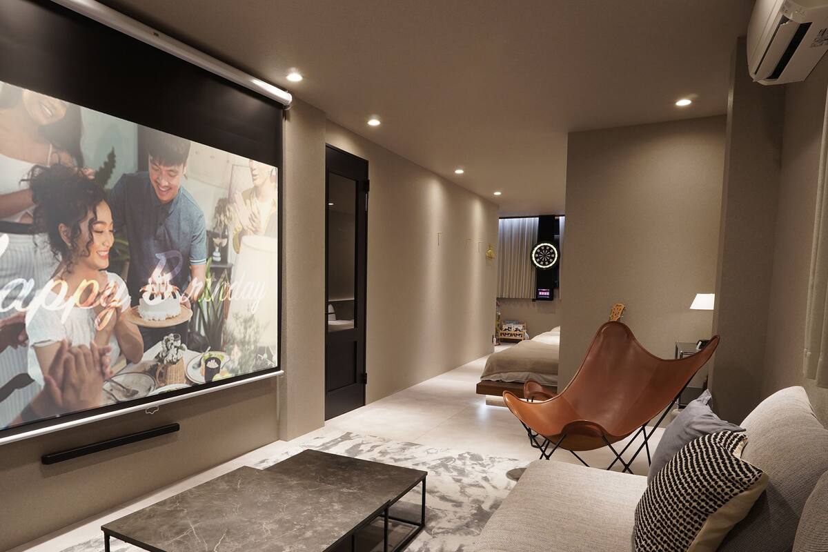 A modern living room with a large flat-screen TV, a comfortable seating area, and a hallway leading to another room.