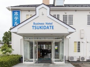 A business hotel with a clear entrance, a signboard, and a visible air conditioning unit.