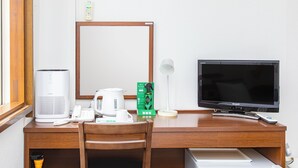 A hotel room with a wooden desk, a white kettle, a remote control, a television, and a trash bin. - Business Hotel Tsukidate (Kurihara)