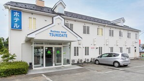 A business hotel with a sign reading 'Business Hotel TSUKIDATE' and a parking lot with a silver car. - Business Hotel Tsukidate (Kurihara)