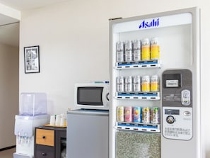 A vending machine with various drinks, a water dispenser, and a microwave.