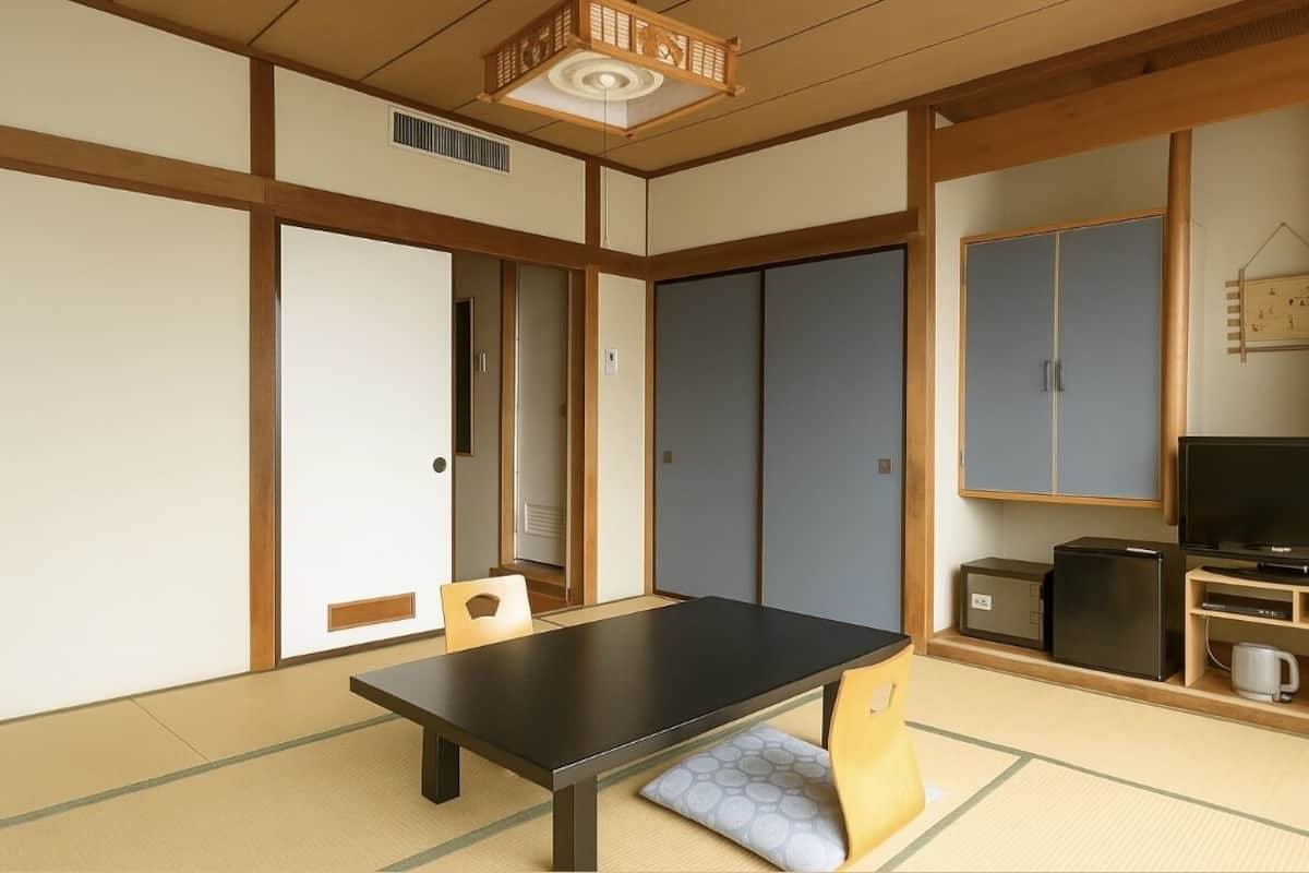 Een traditionele Japanse kamer met tatami vloerbedekking, een lage tafel, schuifdeuren en een televisie.