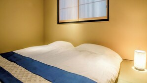 A hotel room with a bed, a nightstand, a lamp, and a window with blinds. - Kyoran Satsukitei (Kyoto)