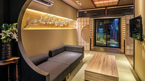 A modern interior with a sofa, a wooden coffee table, and a decorative wall piece. - Kyoran Satsukitei (Kyoto)