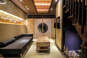 A modern interior with a sofa, a wooden table, and a traditional Japanese screen. - Kyoran Satsukitei (Kyoto)