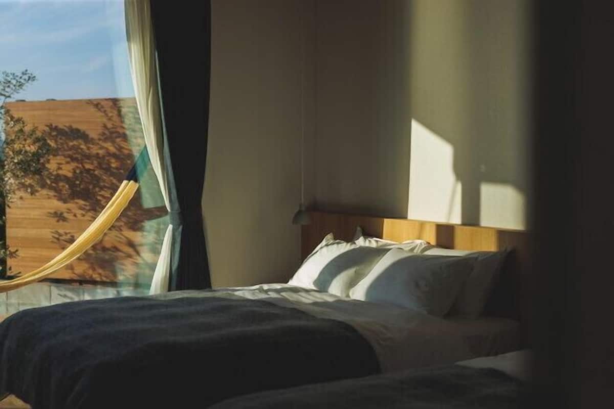 Un dormitorio con cama, ventana con cortinas y vista al paisaje.