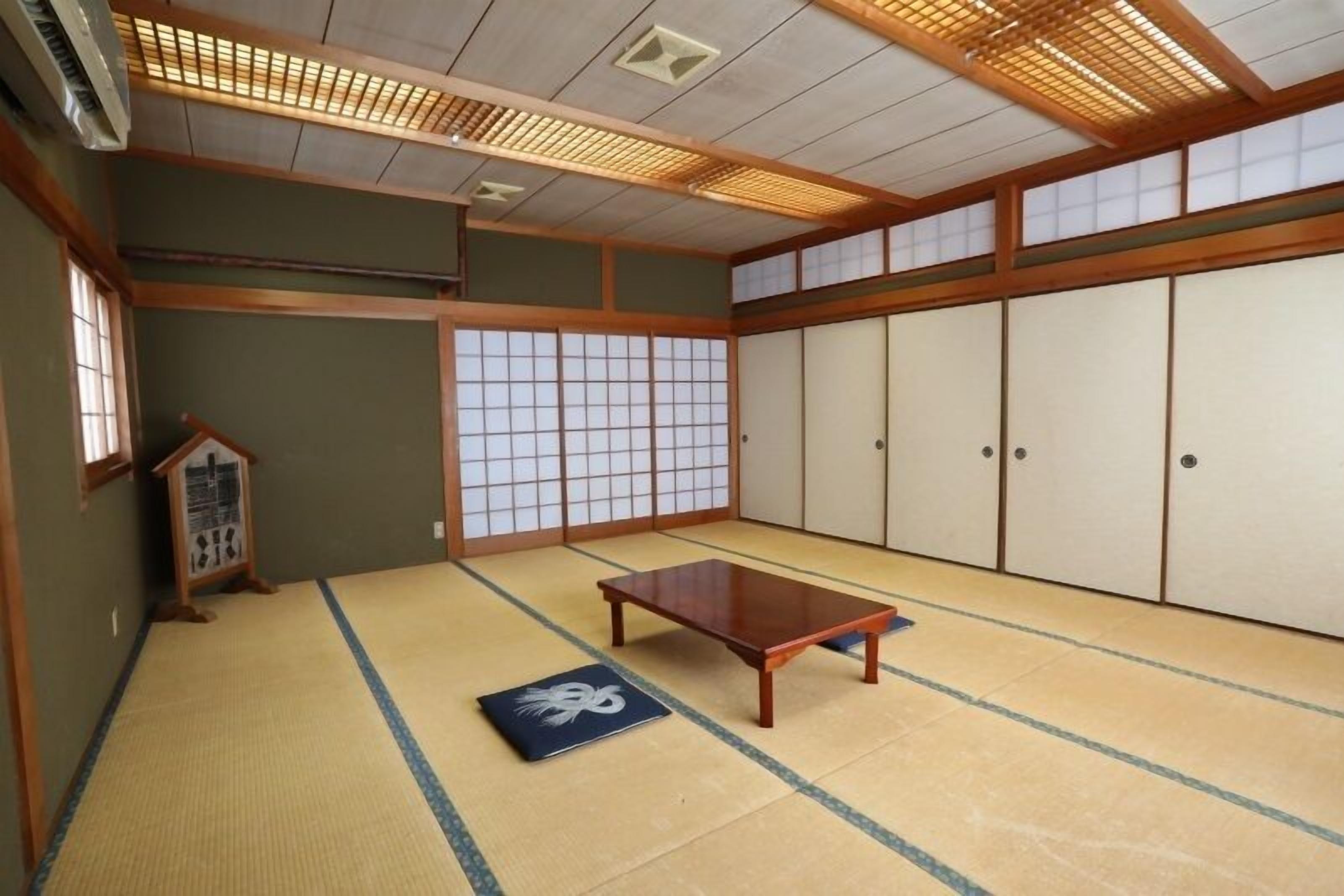 Ein traditioneller japanischer Raum mit Tatami-Böden, Schiebetüren und einem Holztisch.