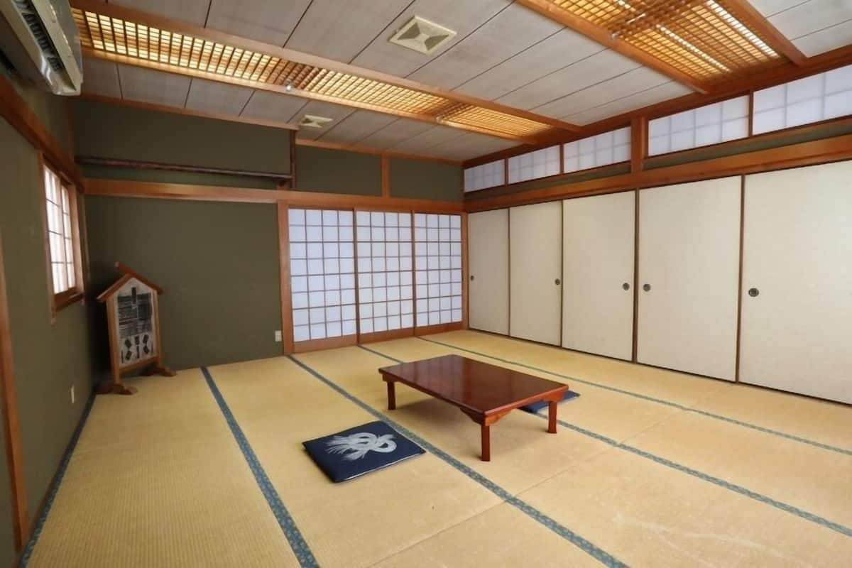 A traditional Japanese room with tatami flooring, sliding doors, and a wooden table.