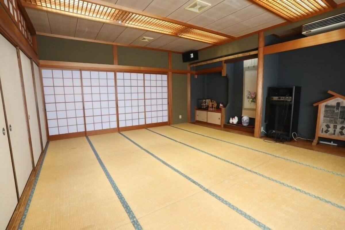 A traditional Japanese room with tatami flooring, sliding doors, and a television.