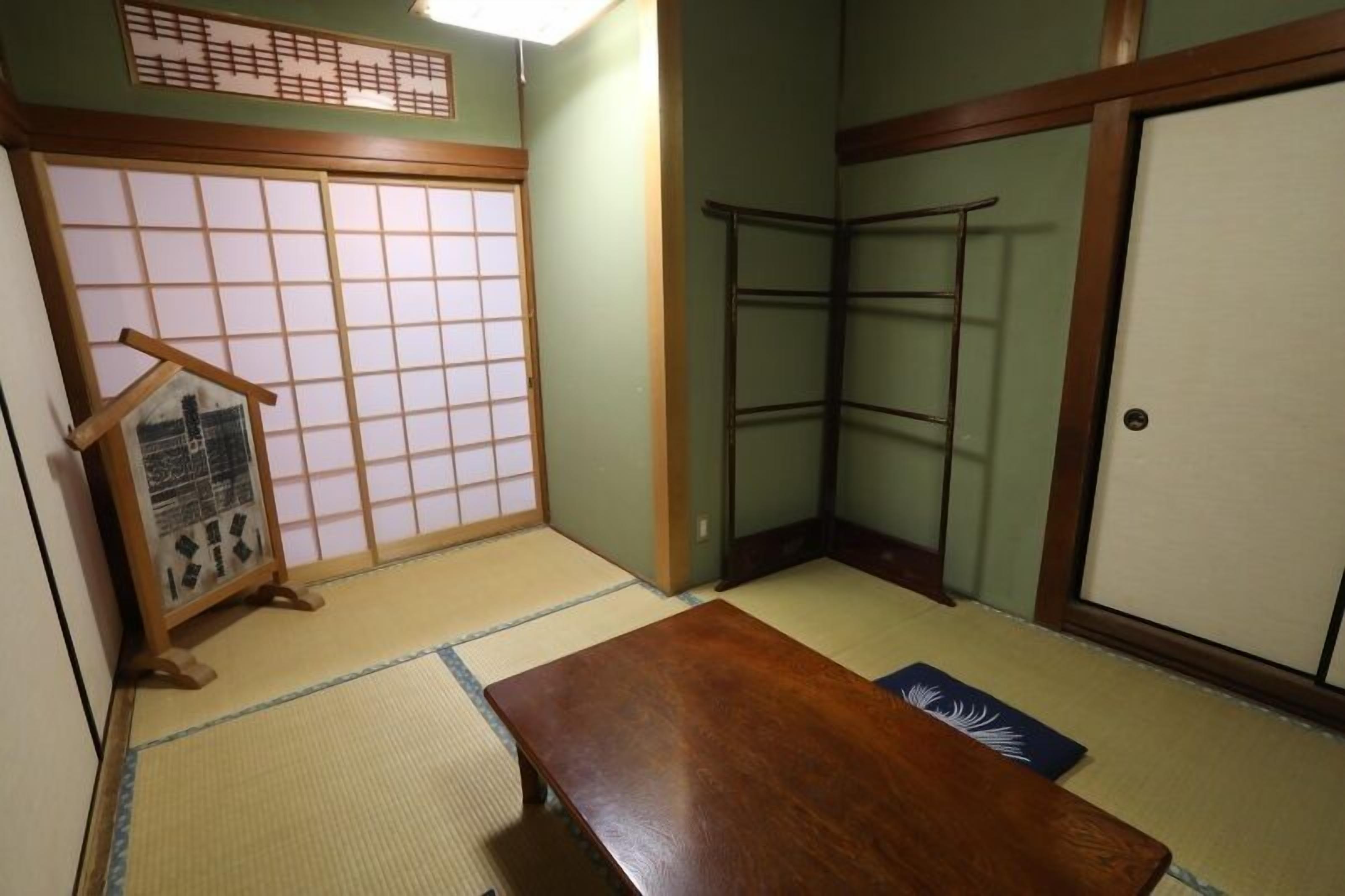 Ein traditioneller japanischer Raum mit Tatami-Bodenbelag, einem Holztisch, einem Shoji-Bildschirm und einer verschiebbaren Tür.