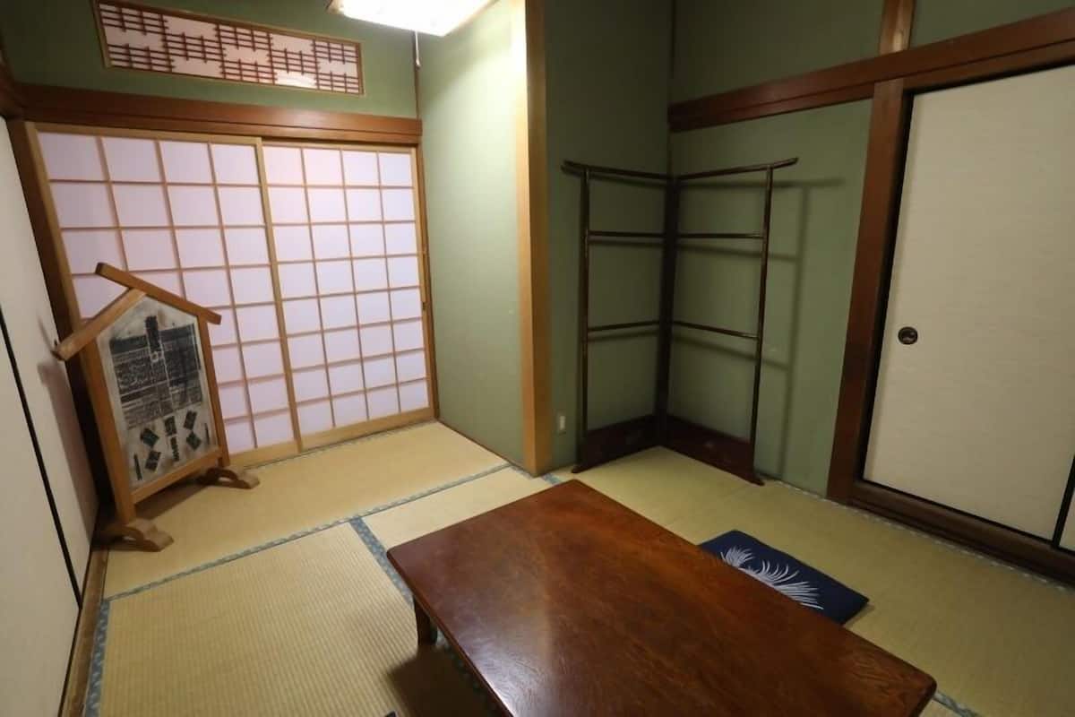 A traditional Japanese room with tatami flooring, a wooden table, a shoji screen, and a sliding door.