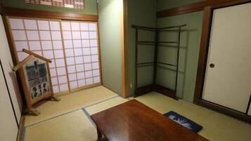 A traditional Japanese room with tatami flooring, a shoji screen, a wooden table, and a wardrobe.