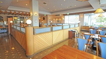 Un restaurante con mostrador de madera, sillas azules y vista al exterior.