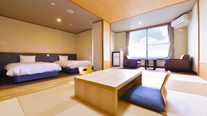 A hotel room with two beds, a desk, chairs, a small table, and a large window offering a view. - Hotel Suiyotei (Atami)