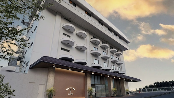 Ein modernes Hotel mit schlichter Fassade, mehreren Balkonen und einem markanten Eingang mit großer Markise.