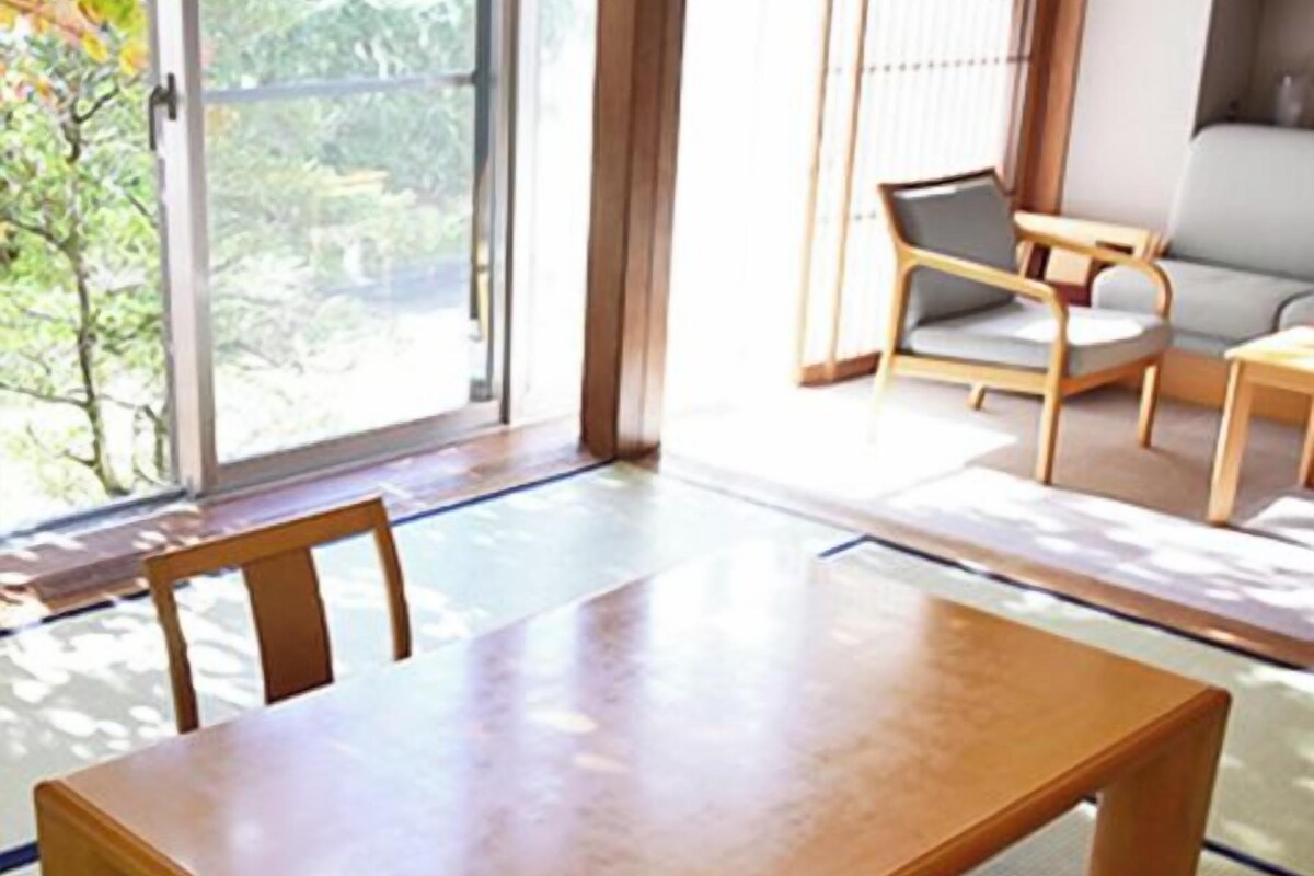 A traditional Japanese-style room with tatami flooring, a low wooden table, and a sofa.