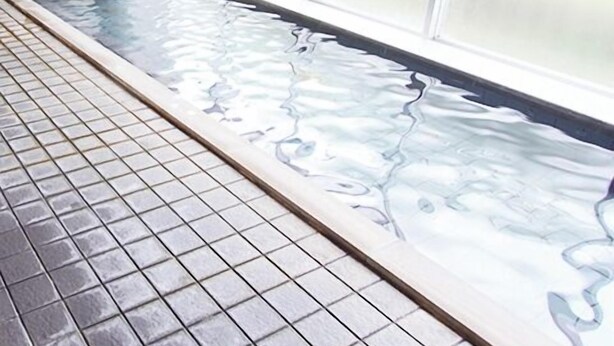 Un área de spa con suelo de baldosas, fuente de agua y grandes ventanales.
