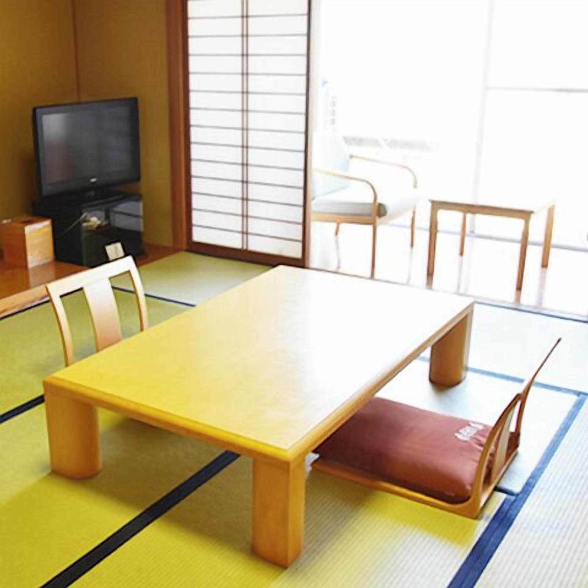A traditional Japanese room with tatami flooring, a low table, and a television.