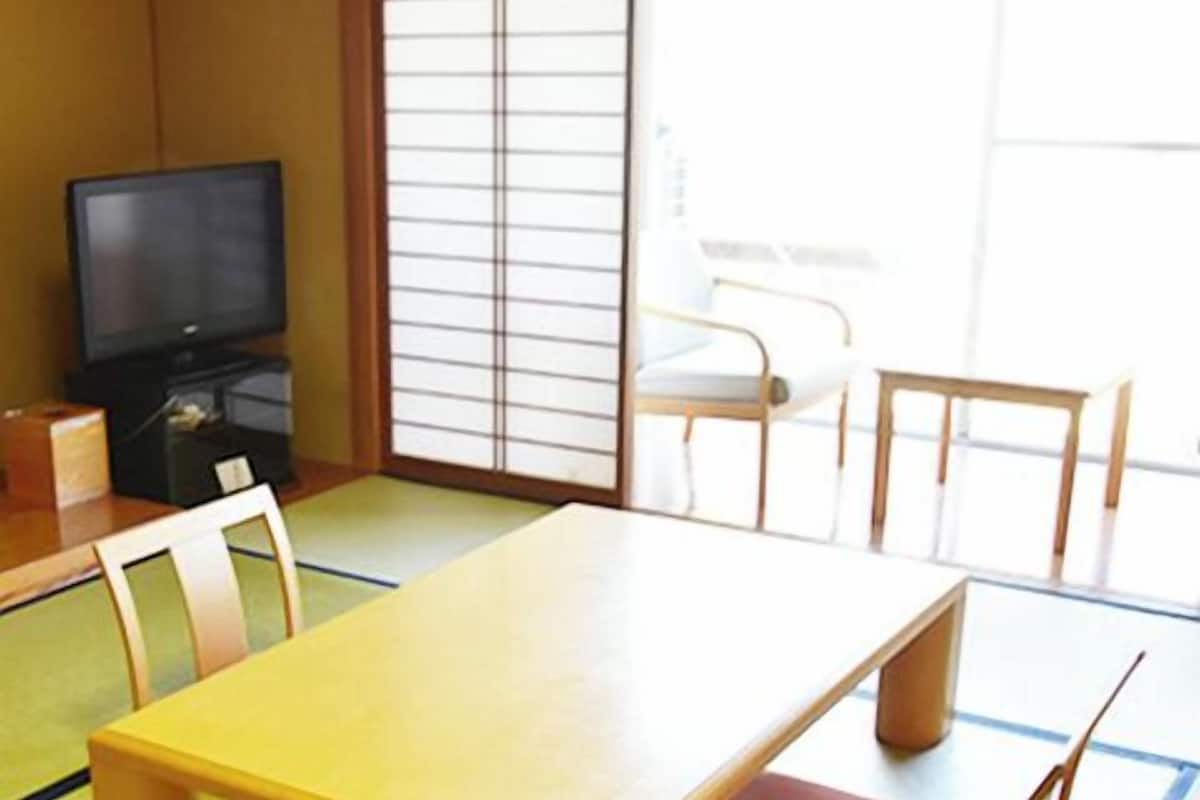 A traditional Japanese room with tatami flooring, a low table, and a television.