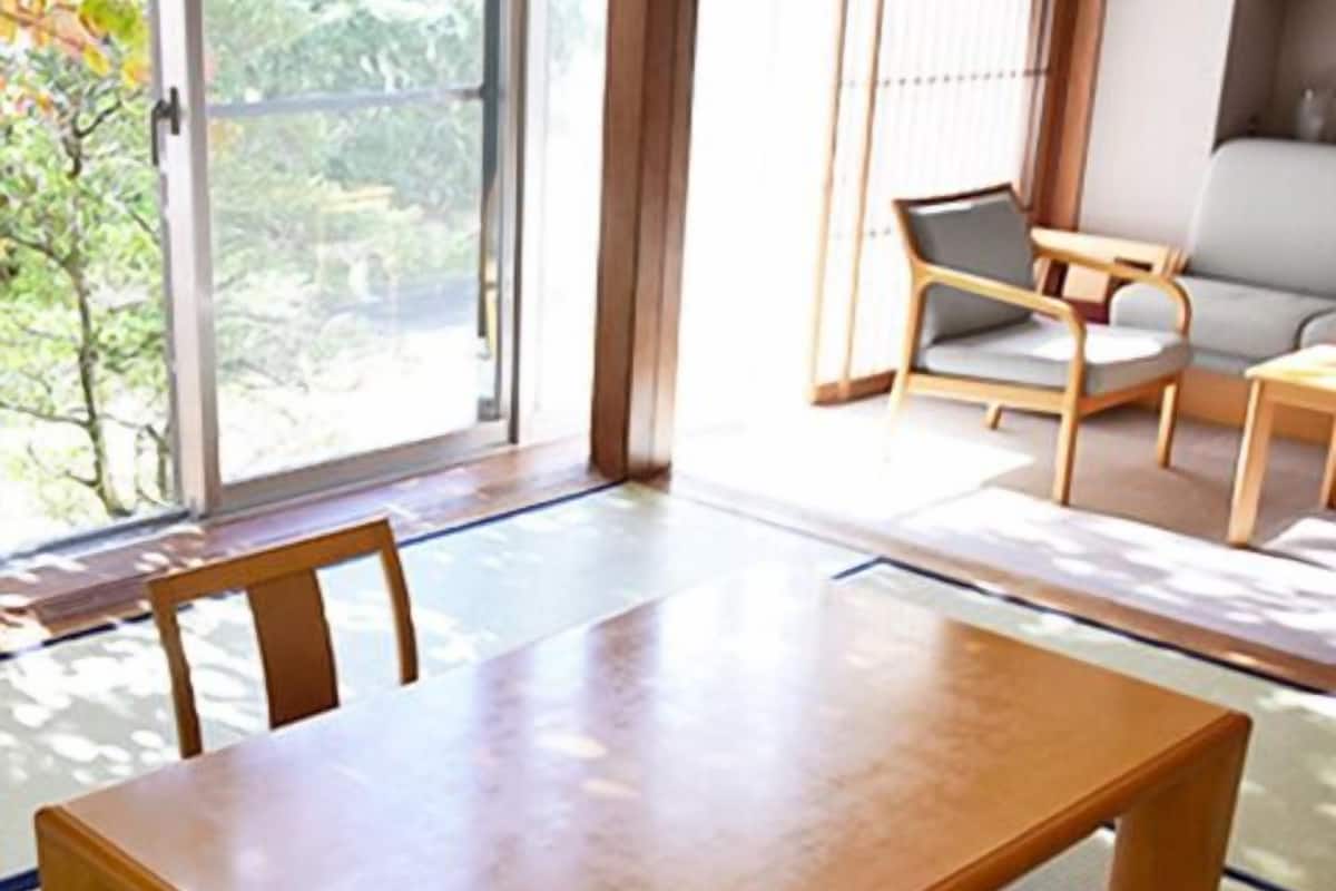 A traditional Japanese-style room with tatami flooring, a low wooden table, and a sofa.