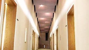 A long, narrow hotel corridor with doors on both sides, a central walkway, and a ceiling with recessed lighting. - Suzumushiso (Matsukawa)