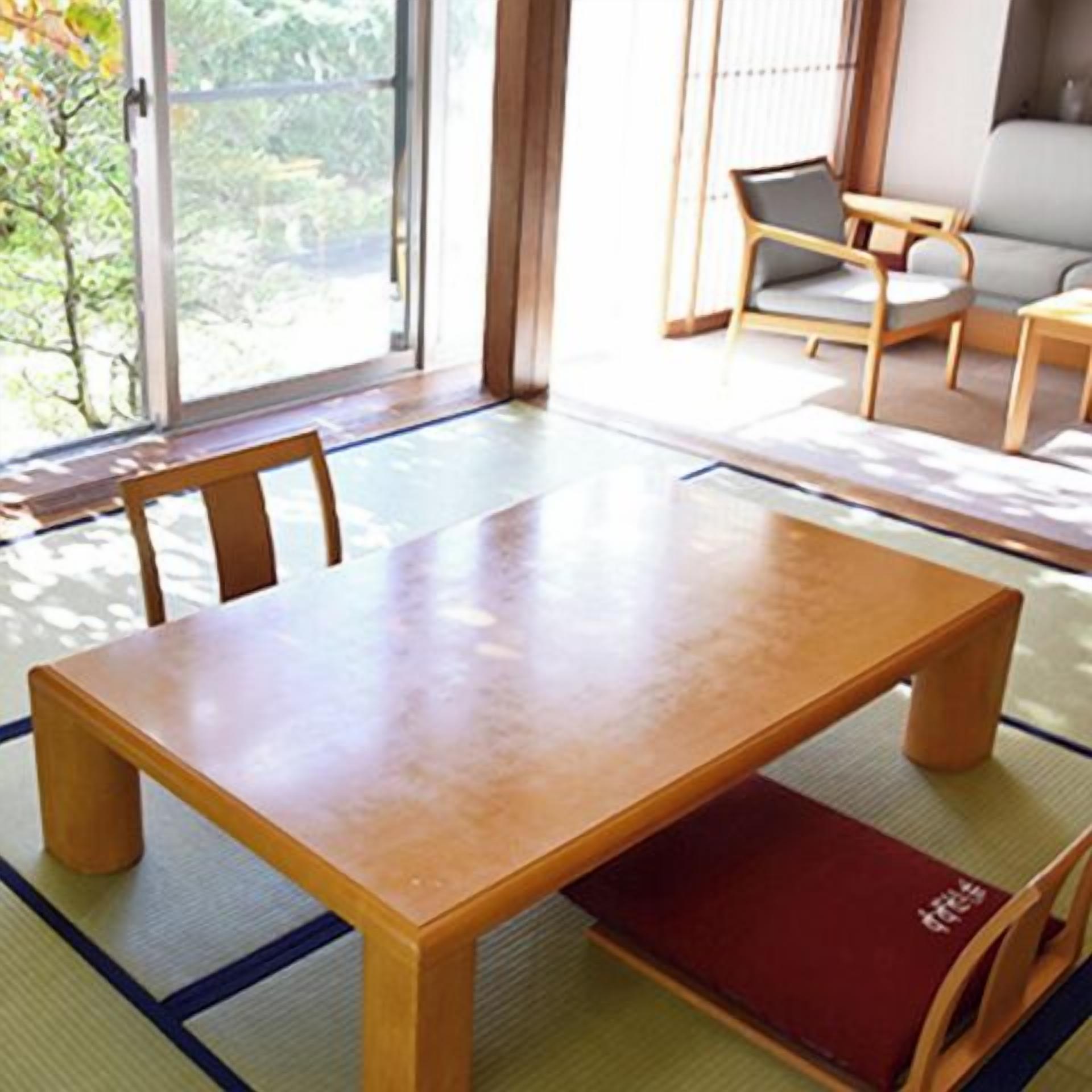 A traditional Japanese-style room with tatami flooring, a low wooden table, and a sofa.