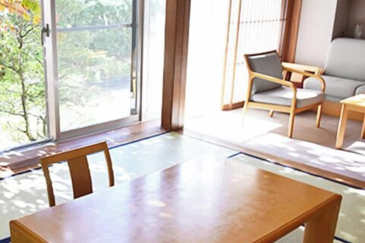 A traditional Japanese-style room with tatami flooring, a low wooden table, and a sofa.
