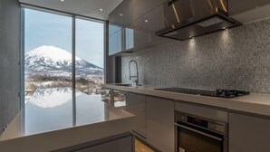 Une cuisine moderne dotée d’une grande fenêtre, d’une hotte en acier inoxydable et offrant une vue sur une montagne enneigée.
