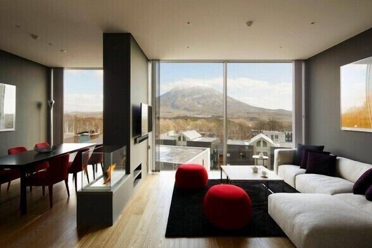 A modern living room with a large window, a dining area, and a sofa.