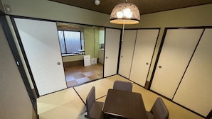 A traditional Japanese-style room with tatami flooring, a low table, and shoji screens. - Kanon House (Kyoto)