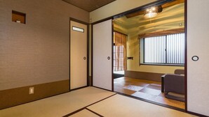 A traditional Japanese room with tatami flooring, sliding doors, and a view of a room with a window and a chair. - Kanon House (Kyoto)