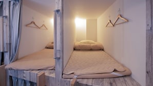 A room with a bed, wooden walls, and two wooden hangers on the wall. - Bnb+ Kanda Terrace Ogawamachi (Tokyo)