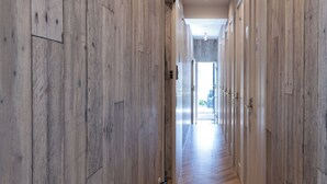 A hallway with wooden paneling and a herringbone floor pattern, leading to a bright room with a large window. - Bnb+ Kanda Terrace Ogawamachi (Tokyo)