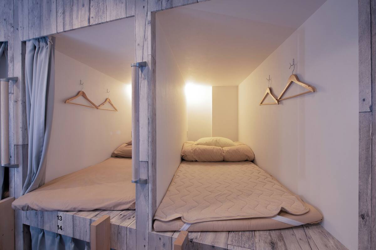 A room with a bed, wooden walls, and two wooden hangers on the wall.