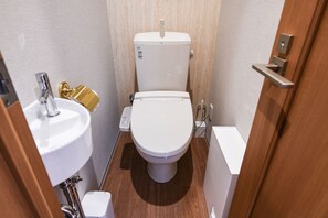 Et lille badeværelse med toilet, håndvask og bruser.