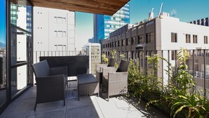 A rooftop terrace with wicker furniture, a wooden ceiling, and a view of city buildings. - Bnb+ Kanda Terrace Ogawamachi (Tokyo)