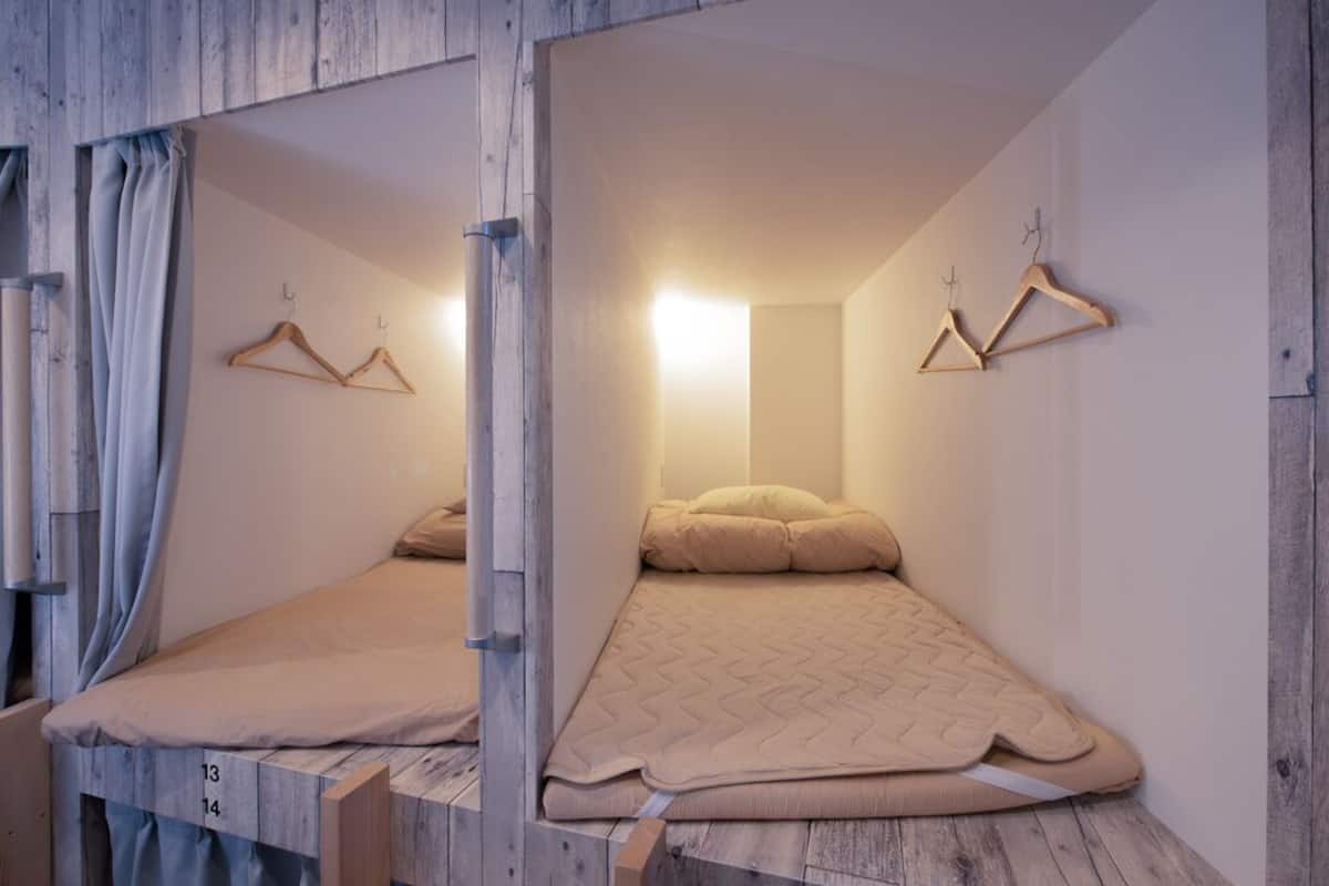A room with a bed, wooden walls, and two wooden hangers on the wall.
