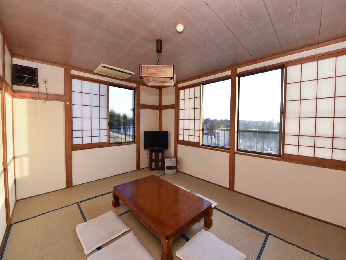 A tatami mat room with a wooden table, sliding doors, and a television.