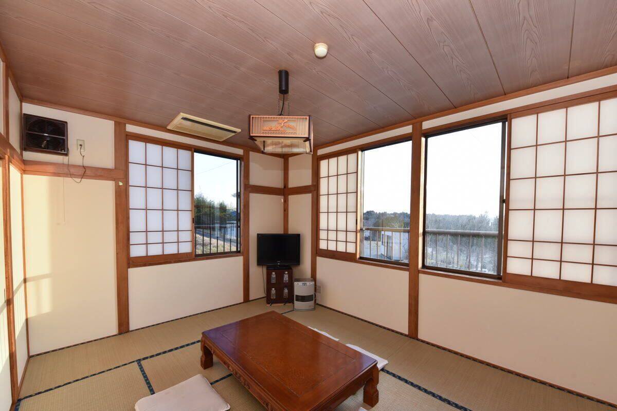 A tatami mat room with a wooden table, sliding doors, and a television.