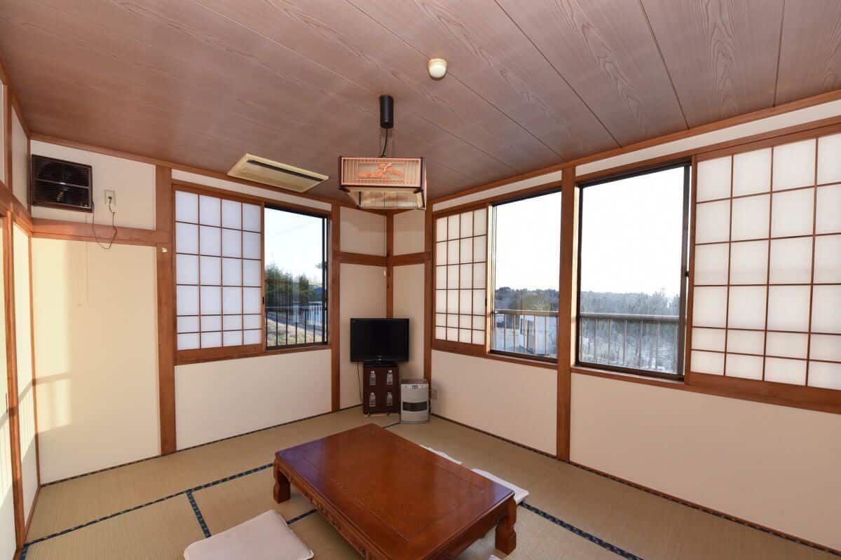 A tatami mat room with a wooden table, sliding doors, and a television.