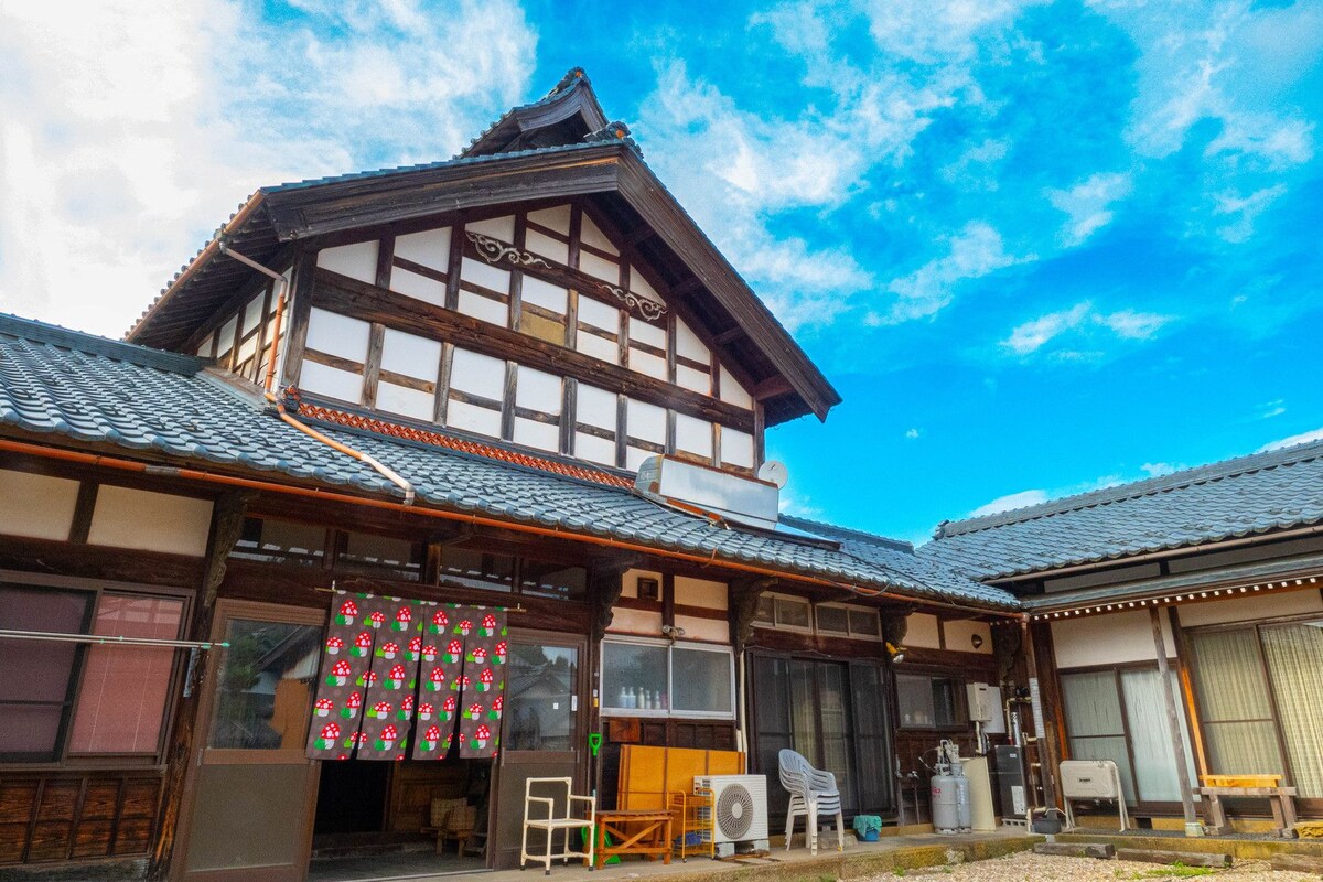 A traditional Japanese building with a tiled roof, wooden beams, and a large window.