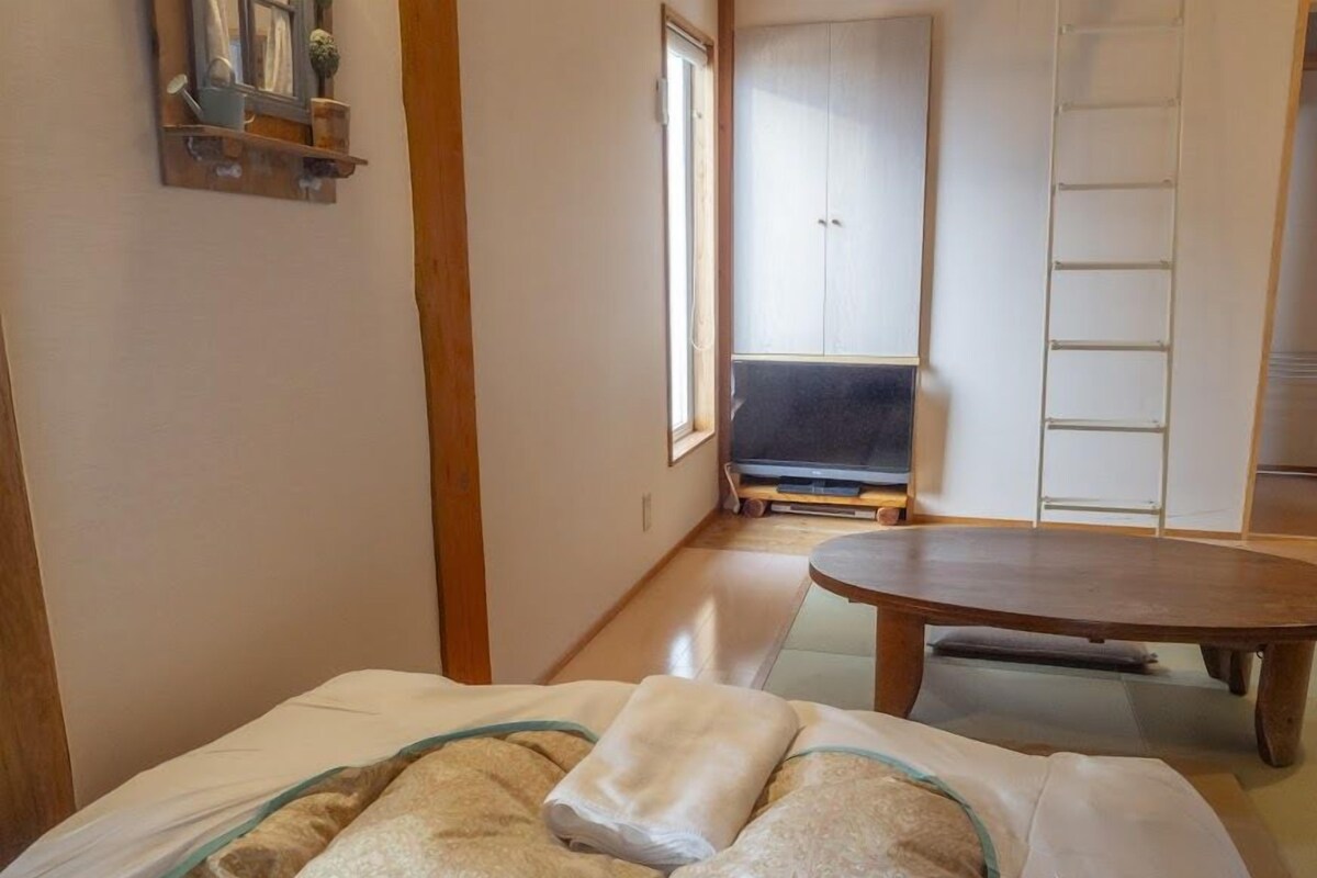 A room with a bed, a wooden table, a wardrobe, and a TV.