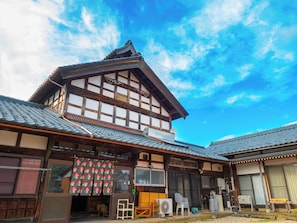 Un edificio japonés tradicional con techo de tejas, vigas de madera y un ventanal grande.