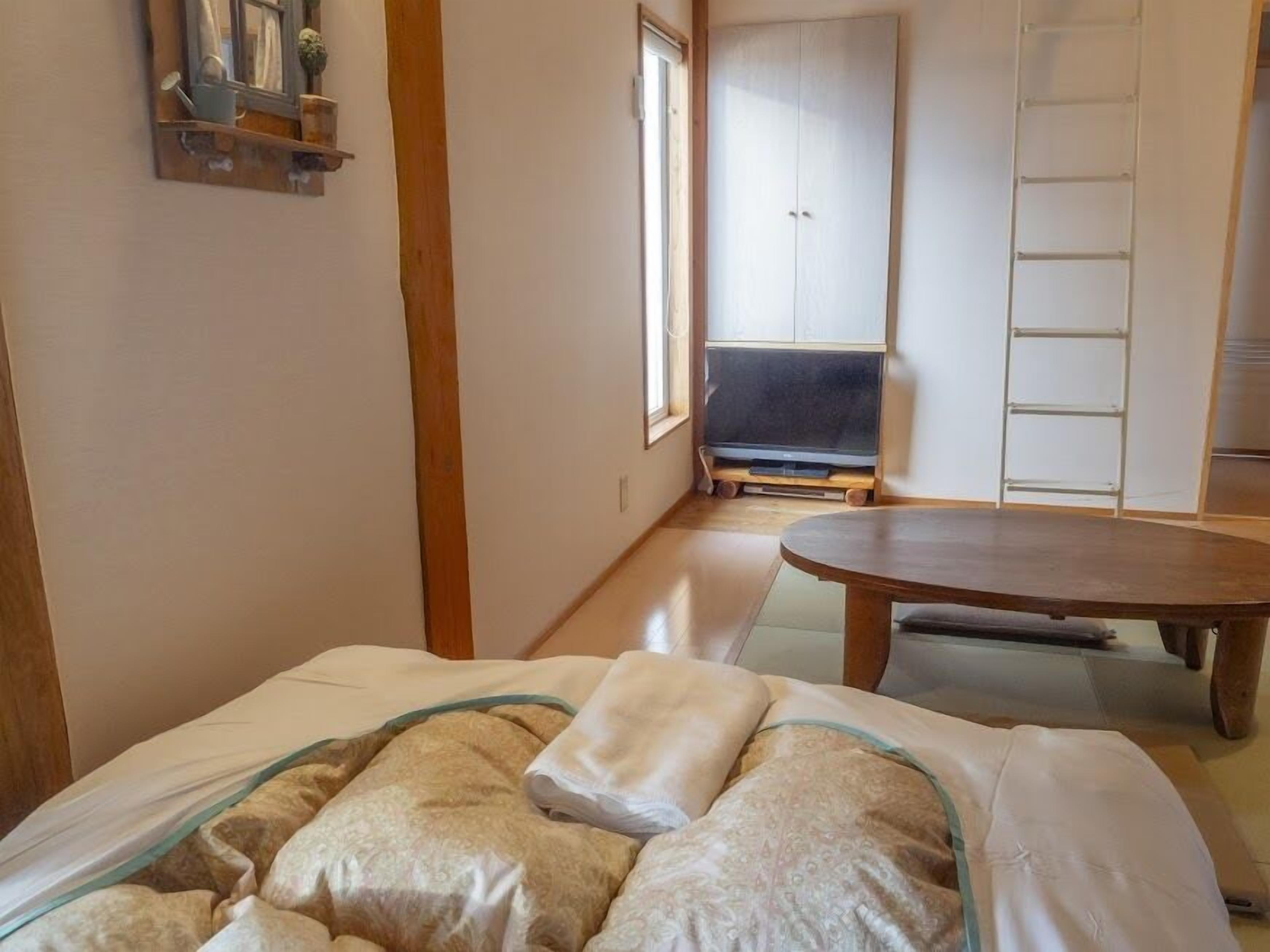 A room with a bed, a wooden table, a wardrobe, and a TV.